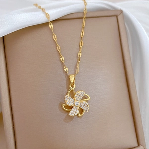 Rotating windmill gold necklace with cubic zirconia pavé on elegant white silk cloth