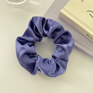 Close-up of a soft purple satin scrunchie showing detailed silk texture and elegant folds
