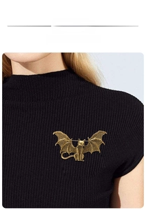 Detail shot of vintage gold bat cat brooch pinned on black knit sweater fabric