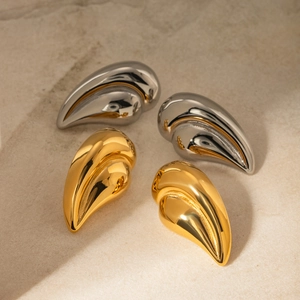 Macro shot of silver and 18k gold teardrop earrings on textured stone surface