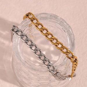 Dettaglio di collane a catena cubana da 8mm in oro e argento su un barattolo di vetro