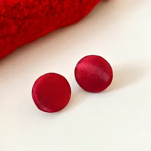Orecchini a perno tondi in velluto rosso con texture spazzolata su uno sfondo bianco