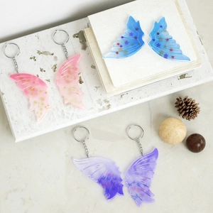 Glittering butterfly resin keychain pendants in pink, blue, and purple colors