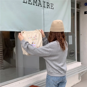 Détail d'un sac en velours côtelé beige avec texte 'LET'S GO PICNIC' brodé