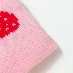 Close-up of pink knitted hat fabric featuring red heart patterns and soft wool texture