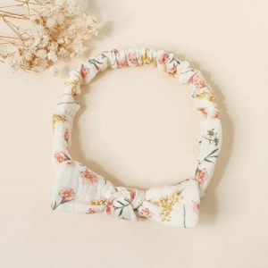Detail of floral baby headband with a cute bow on textured cotton cream fabric