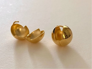 Detail of gold ball hoop earrings showing the hinged closure and polished finish