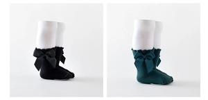 Detail of baby cotton socks featuring large satin bows and ruffle trim in black and green
