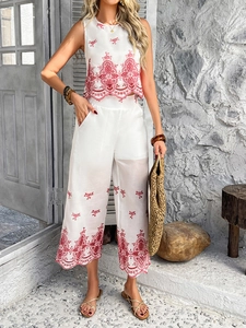 Detail of white sleeveless top and wide-leg trousers with red floral embroidery