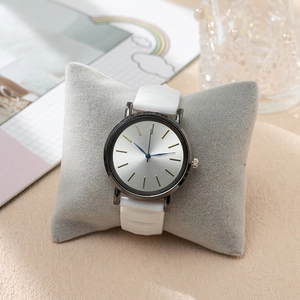 Minimalist quartz watch with white silicone strap and silver dial on a display pillow
