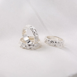 Three silver titanium steel rings with hammered texture displayed on white fabric