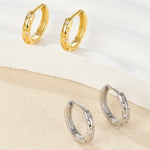 Detail of star-embossed hoop earrings in gold and silver finish with zircon stones