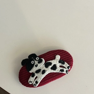 Macro detail of red knitted oval hair clip with cute embroidered dalmatian dog pattern