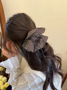 Detail of vintage plaid bow hair scrunchie with black ribbons on a low ponytail hairstyle