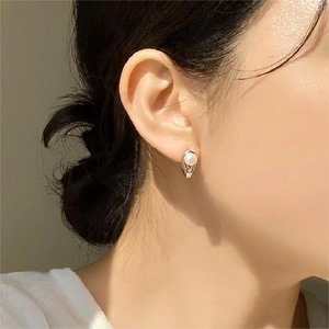 Close-up of minimalist pearl hoop earring on model showing elegant silver metal setting