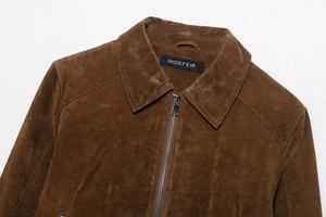 Détail d'une veste en daim marron avec col à revers vintage et fermeture éclair