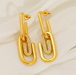 Gros plan sur des boucles d'oreilles trombones dorées serties sur de la soie blanche