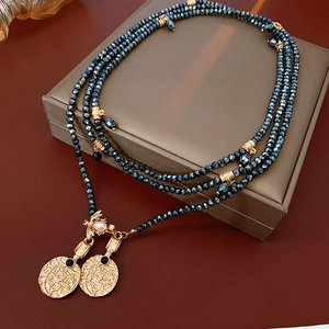 Close-up of vintage gold coin pendants and dark blue crystal beads on a leather box