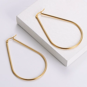 Boucles d'oreilles créoles gouttes en acier titane avec finition dorée polie sur support blanc