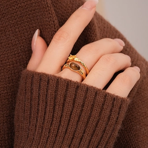 Detailed close-up of stacked 18k gold rings featuring tiger eye stone and lava texture