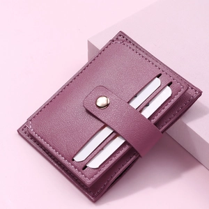 Close-up of a purple leather card holder with snap button on pink geometric prop