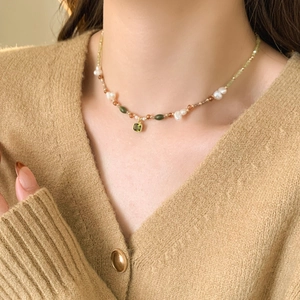 Detail of vintage 18k gold plated necklace with freshwater pearls and green zircon pendant