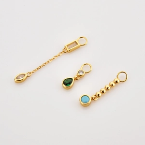 Macro detail of three gold earrings with colorful zircon and marquise stones