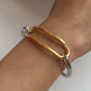 Detail of two-tone gold and silver geometric stainless steel bracelet on model wrist