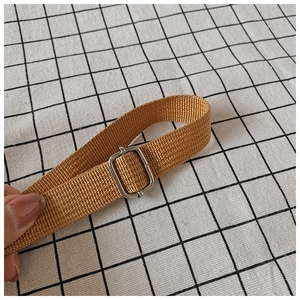 Detailed close-up of brown woven nylon shoulder strap with adjustable metal buckle