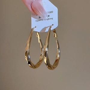 Macro view of gold twisted teardrop hoop earrings with high-gloss polished metallic finish