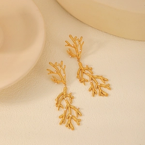Boucles d'oreilles corail doré avec perles blanches sur un fond texturé élégant