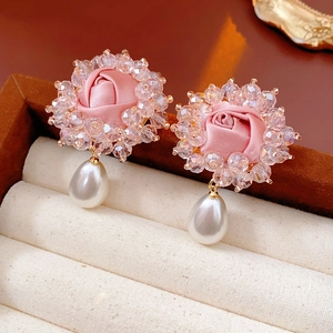 Detailed macro view of pink fabric floral earrings with white teardrop pearl pendants