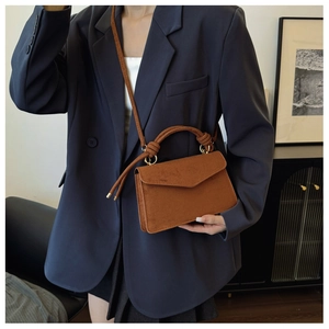 Brown frosted suede crossbody bag with woven handle and gold hardware on a model