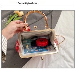 Capacity view of a red embroidered satin bag featuring a bamboo handle and golden clasp