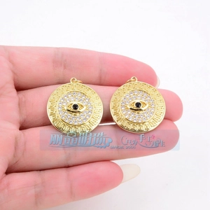 Detail showing golden evil eye charms with white zircon inlay and Greek fret pattern
