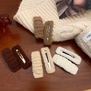 Detailed view of plush ribbed hair clips in warm brown and cream tones on knit fabric