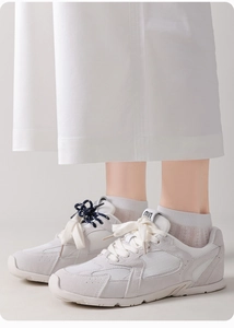 Detail of white mesh and suede panel sneakers with lace-up closure on feet