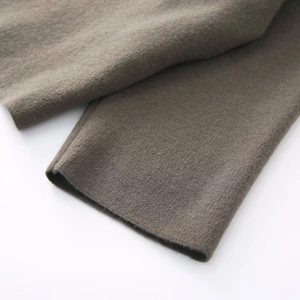 Close-up of premium taupe knit fabric showing fine texture of the asymmetric poncho