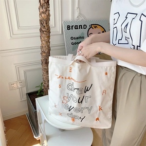 Minimalist white canvas tote bag with black hand-drawn lettering and orange accents