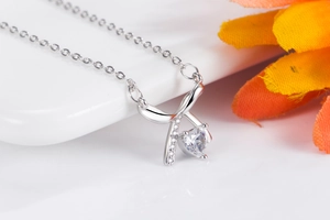 Detailed close-up of a silver bow and heart-shaped zircon pendant with a floral accent