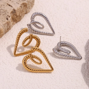 Macro view of gold and silver heart-shaped twisted rope earrings on stone texture