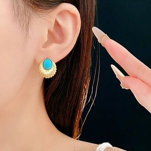 Detail of vintage fan-shaped gold stud earring with oval turquoise stone on model