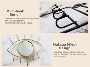Wall-mounted eye-shaped jewelry organizer with gold finish, mirror, and hanging hooks