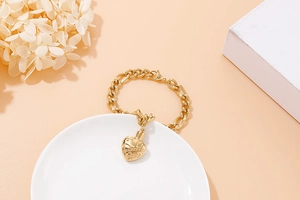 Detailed macro view of a gold heart-shaped locket pendant with vintage floral engravings