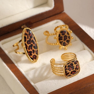 Three gold leopard print stainless steel rings with adjustable bands in a wooden jewelry box