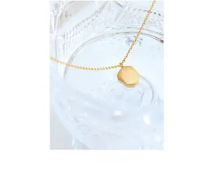 Macro detail of brushed gold geometric pendant on fine chain necklace in crystal glass