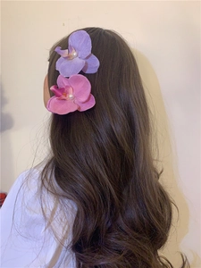 Detail view of pink and purple Phalaenopsis orchid hair clips with white pearls on long hair