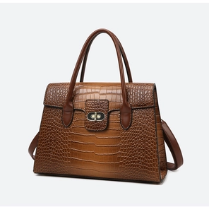 Detailed close-up of brown crocodile texture leather and metallic twist lock on handbag
