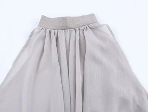 Detailed view of light gray chiffon top featuring elegant waist pleats and fabric texture