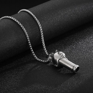 Detailed macro shot of a silver lion head whistle pendant on a textured dark surface